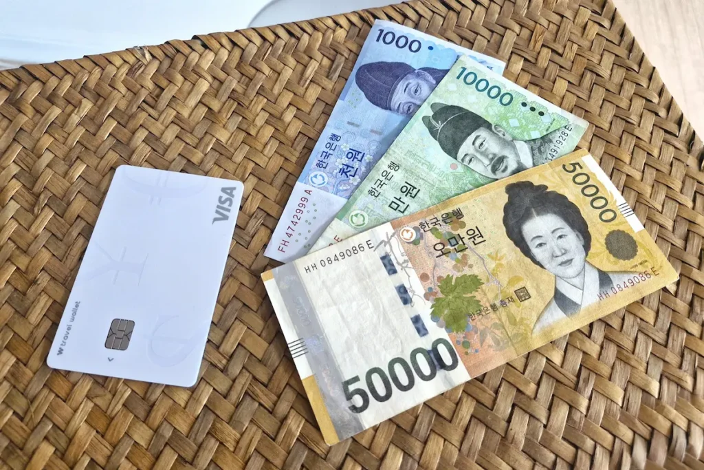 Korean won banknotes, a credit card, and a wallet on a cafe table in Seoul.