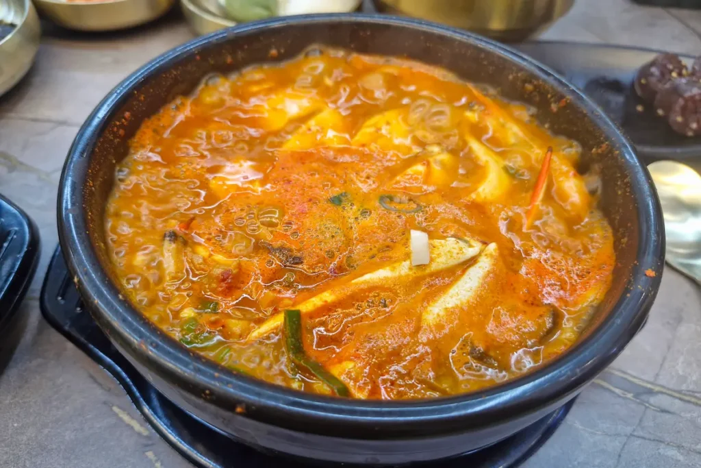 A bubbling pot of spicy sundubu jjigae with soft tofu, seafood, and vegetables.
